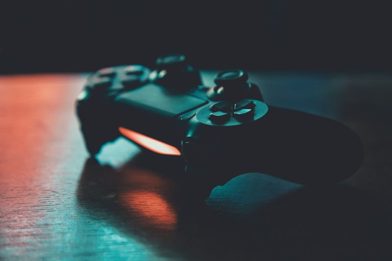 A game controller on a wooden surface lit in blue and orange