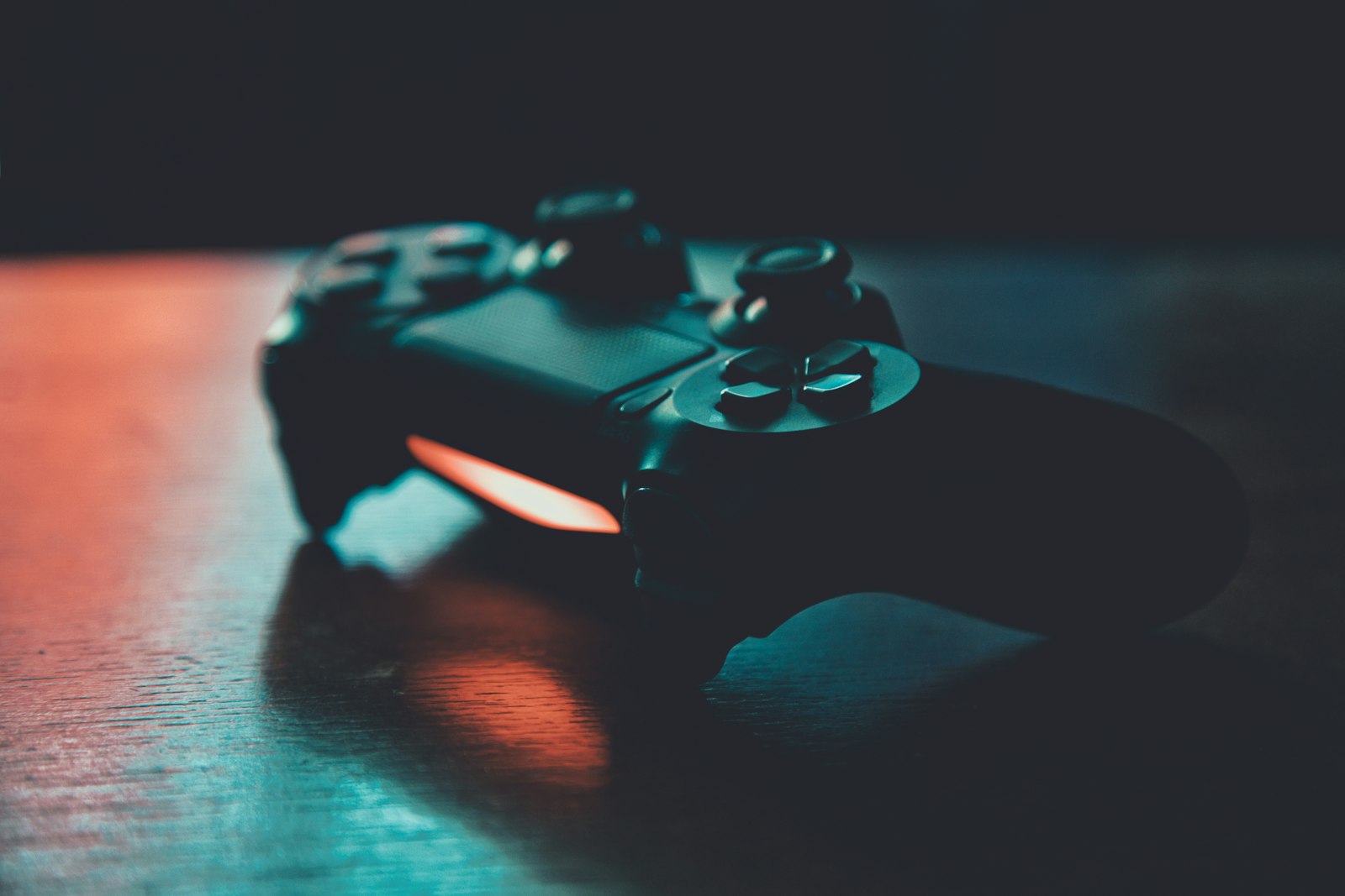 A game controller on a wooden surface lit in blue and orange