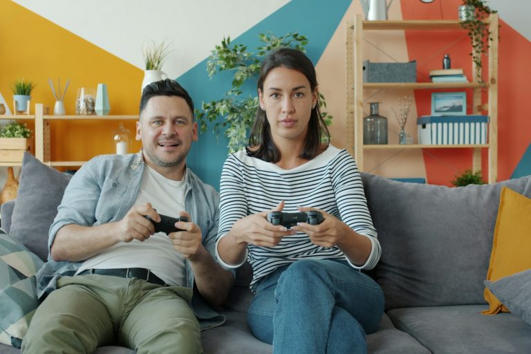 A couple playing video games together on a sofa