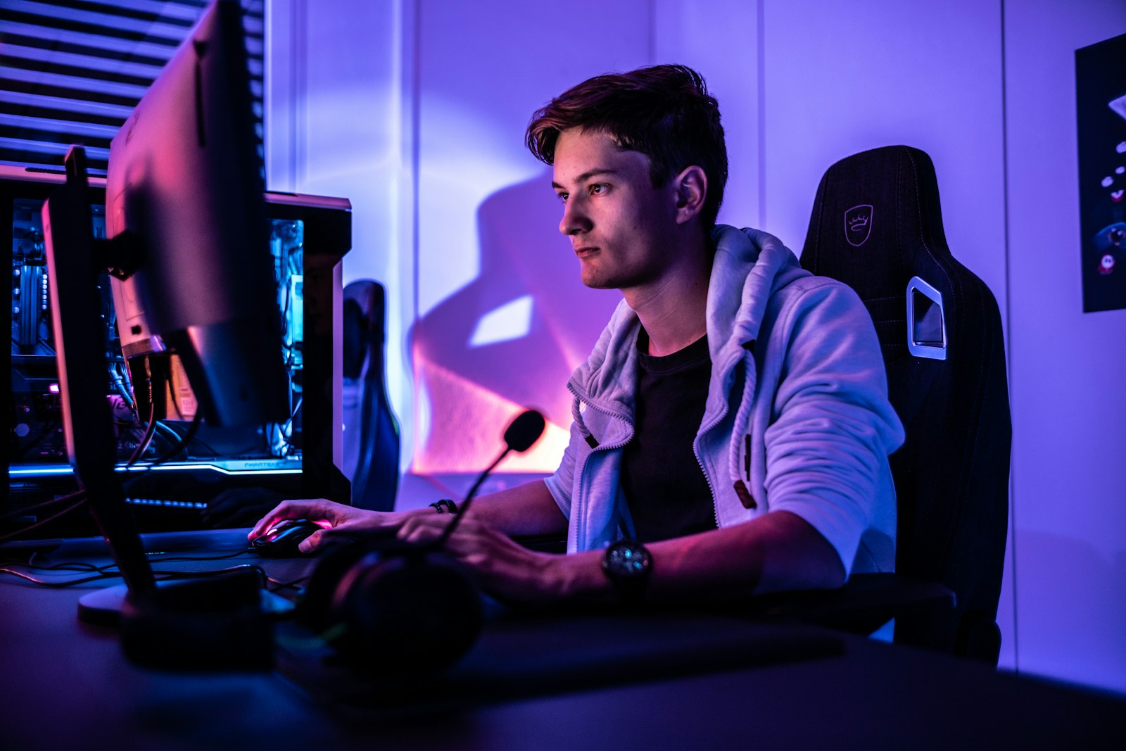 A player at a PC in a room lit with purple light