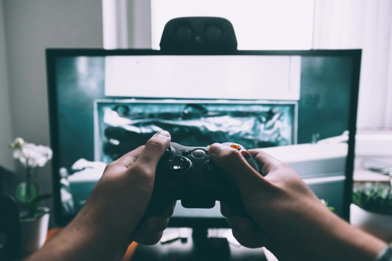 Hands holding a game controller in front of a screen